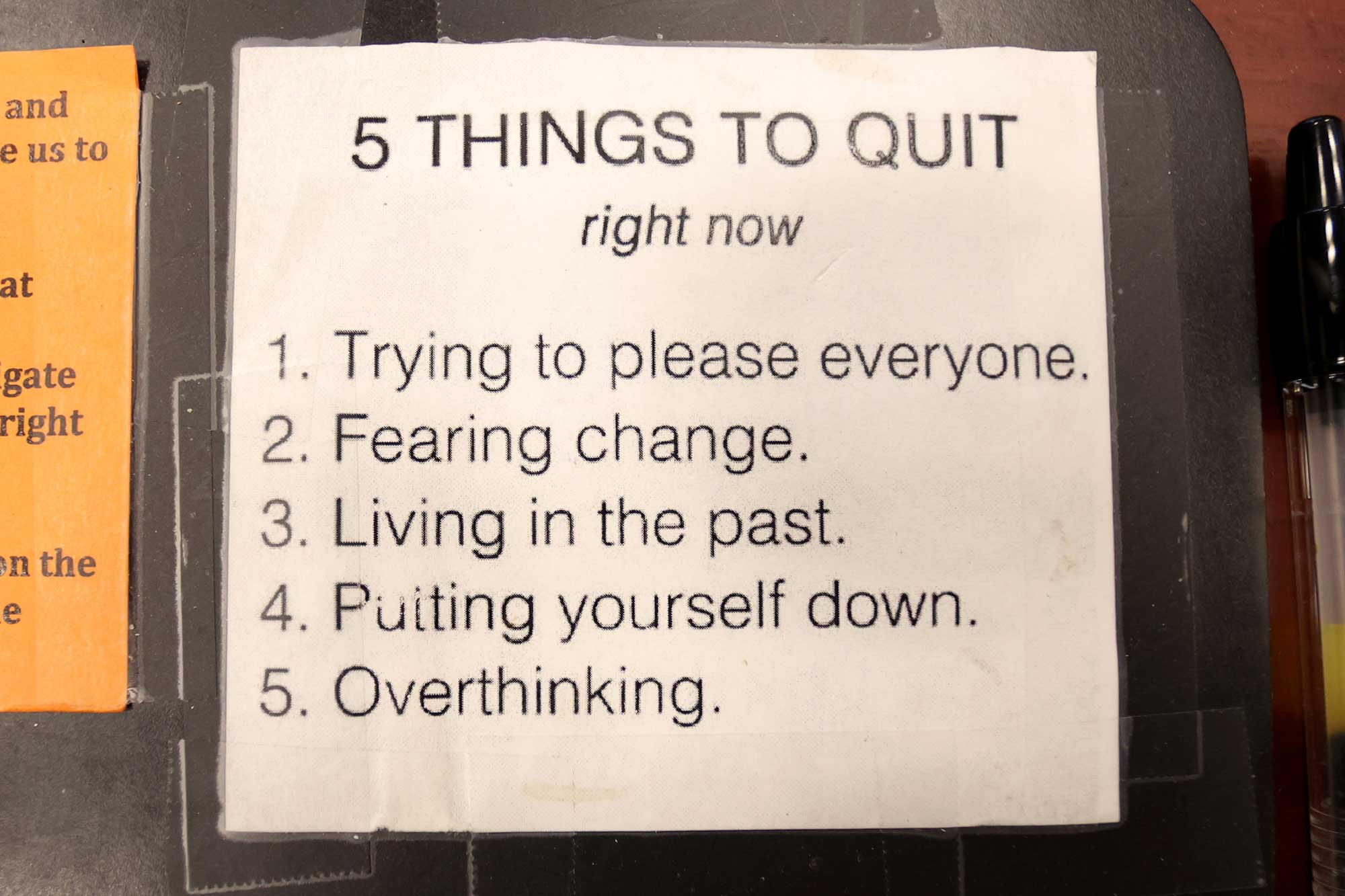 A laminated piece of paper that says 5 things to quit right now. 1. Trying to please everyone. 2. Fearing change. 3. Living in the past. 4. Putting yourself down. and 5. Overthinking.