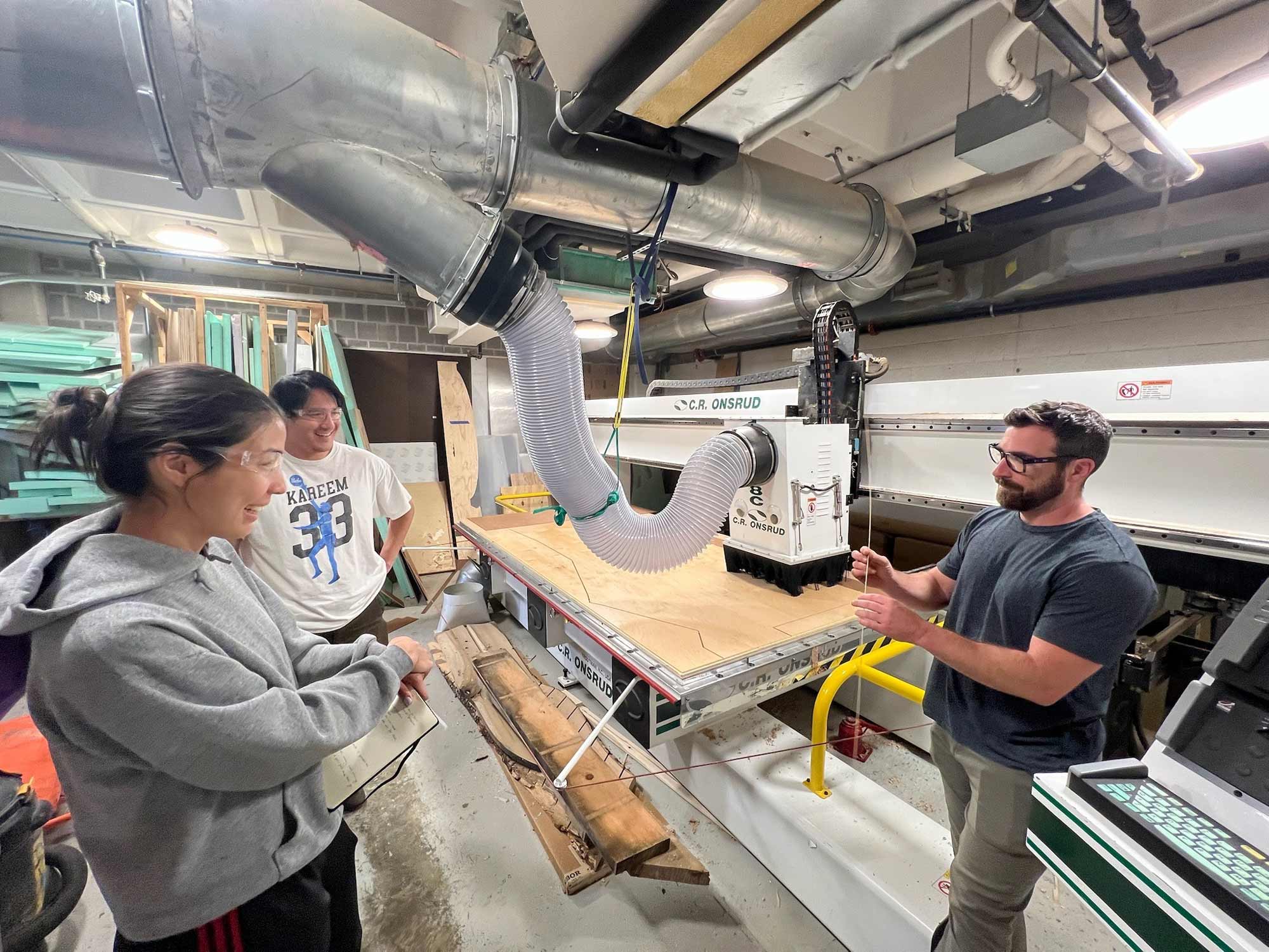 Avery Edson, Paul Bourdin and Trevor Kemp using a CNC machine to cut plywood for the reflection space at UVA Student Health and Wellness