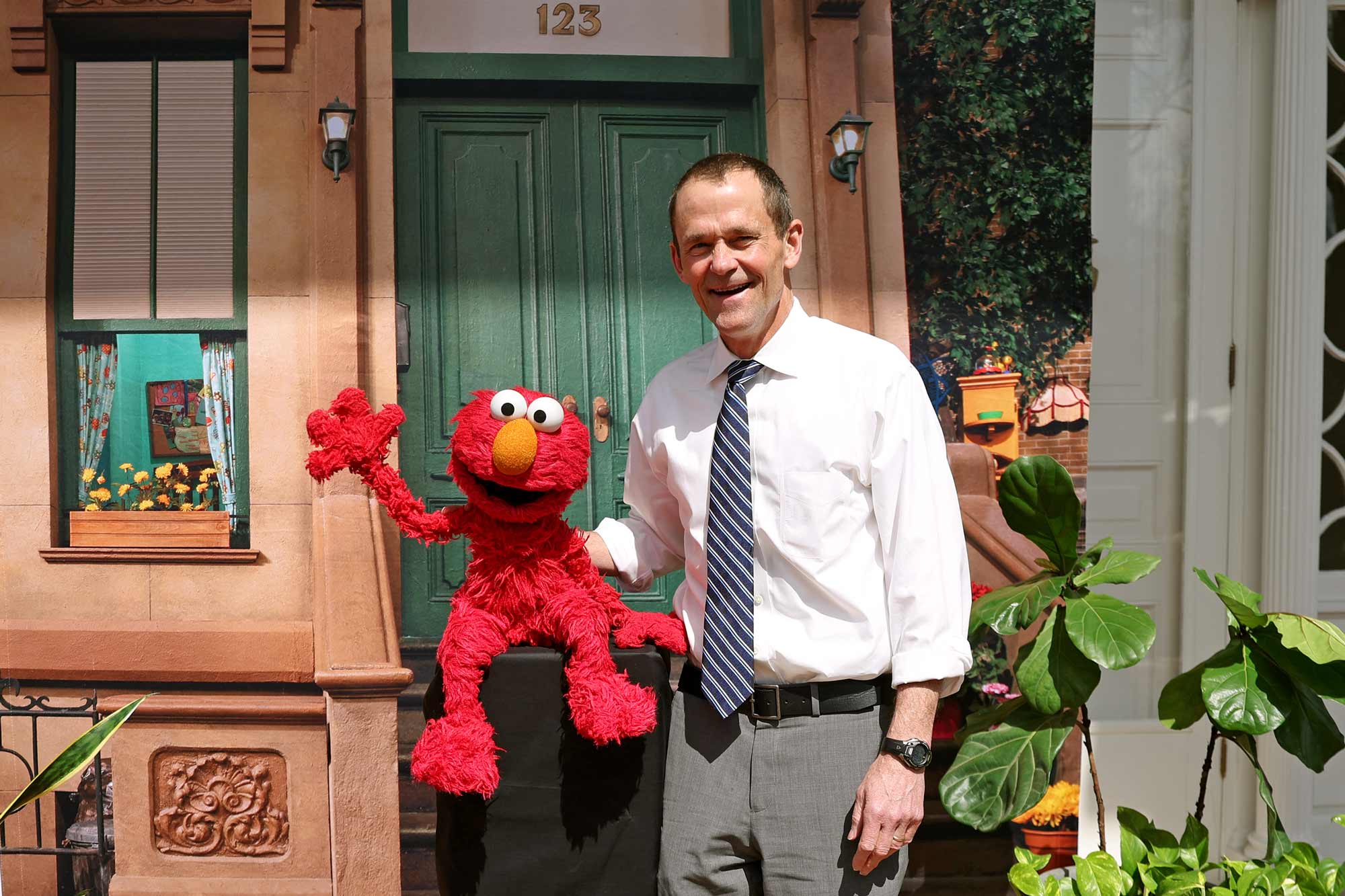 President Jim Ryan poses with Elmo in front of a Sesame Street backdrop.