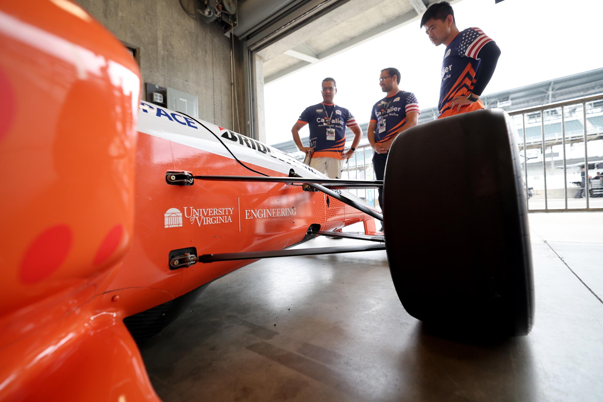 Professor Madhur Behl and members of the Cavalier Autonomous Racing Team behind their autonomous racecar at Indianapolis Motor Speedway.