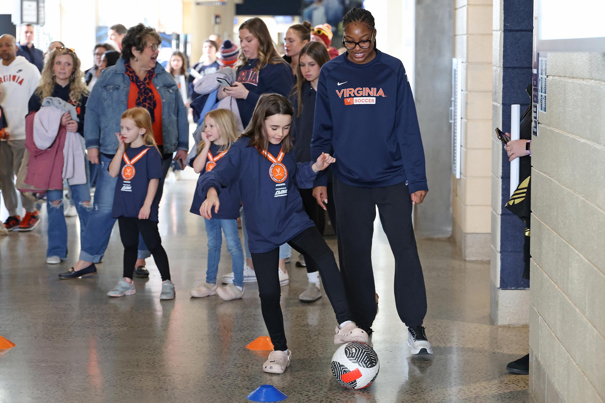 Sophomore Aniyah Collier, a defender on the UVA women’s soccer team, helps a young fan learn how to dribble and trap a soccer ball.