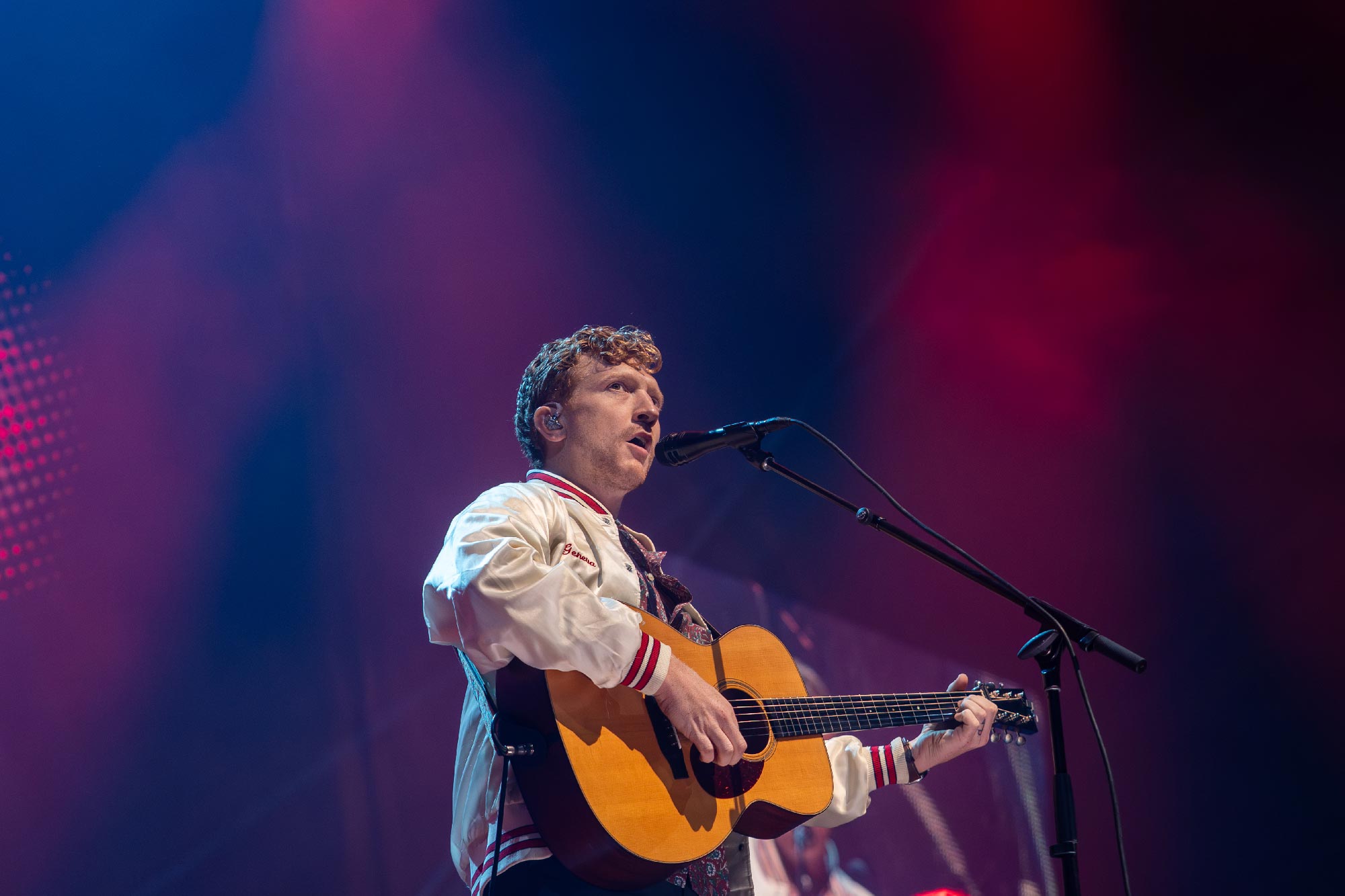 Tyler Childers holding his guitar and singing at UVA's John Paul Jones Arena