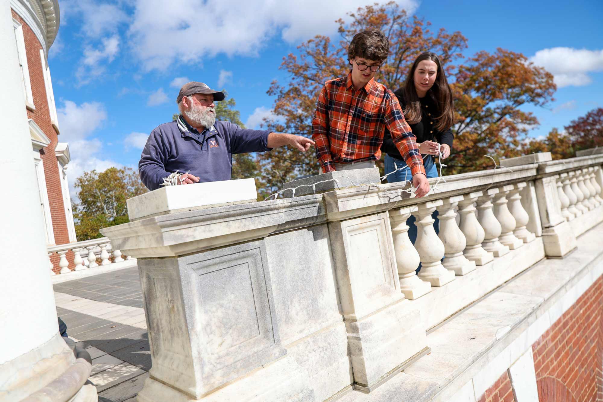 Staff working with students to hang lights along the railings of the Rotunda portico in advance of the 2025 Lighting of the Lawn