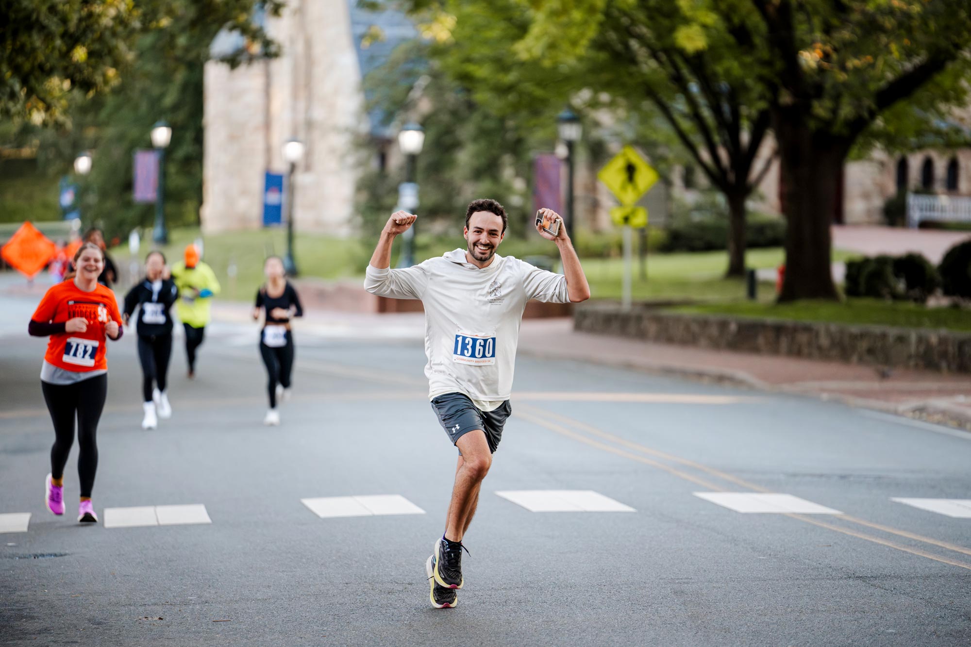 A runner puts hands in the air in a smiling celebration