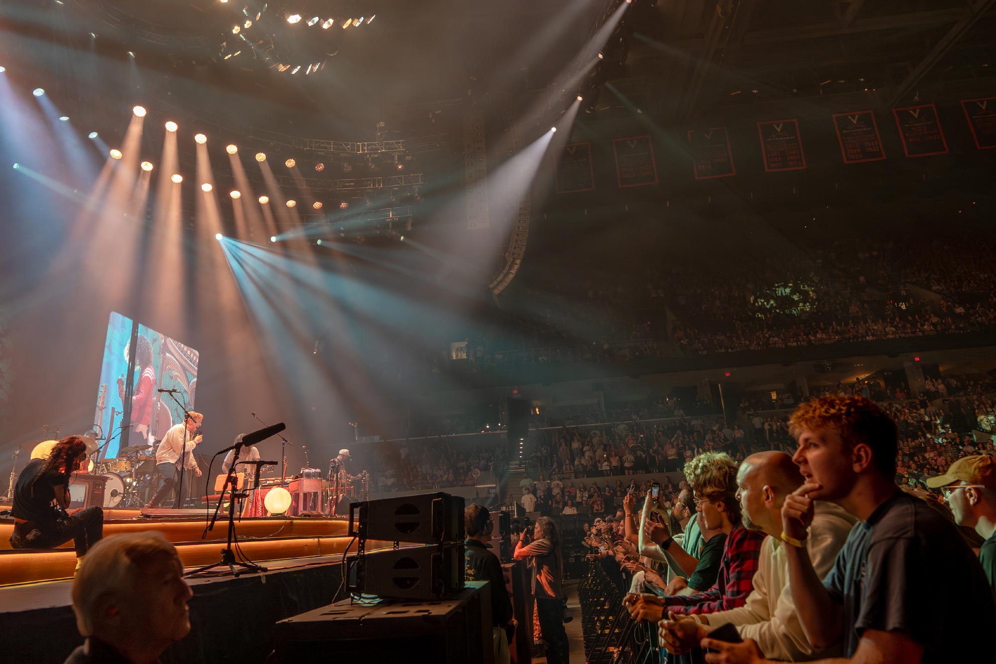 a split shot of Tyler Childers and the Food Stamps on stage with the front and right side of the audience at John Paul Jones Arena