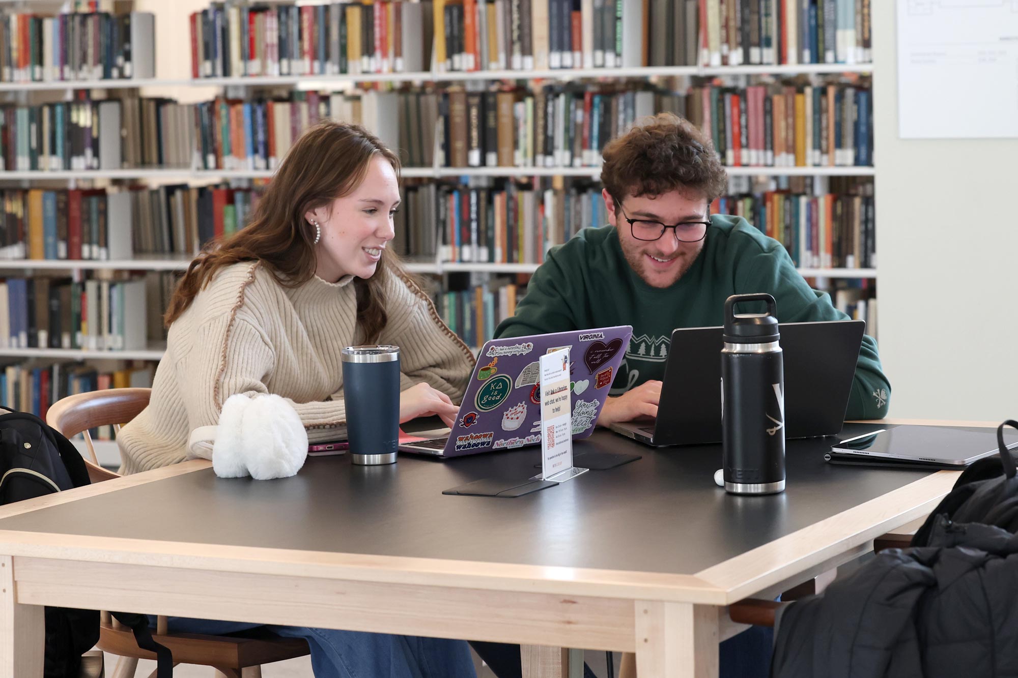 Two students sit together and work in the library