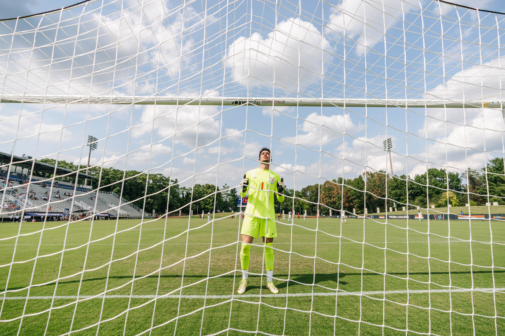 A soccer player in view through the goal netting