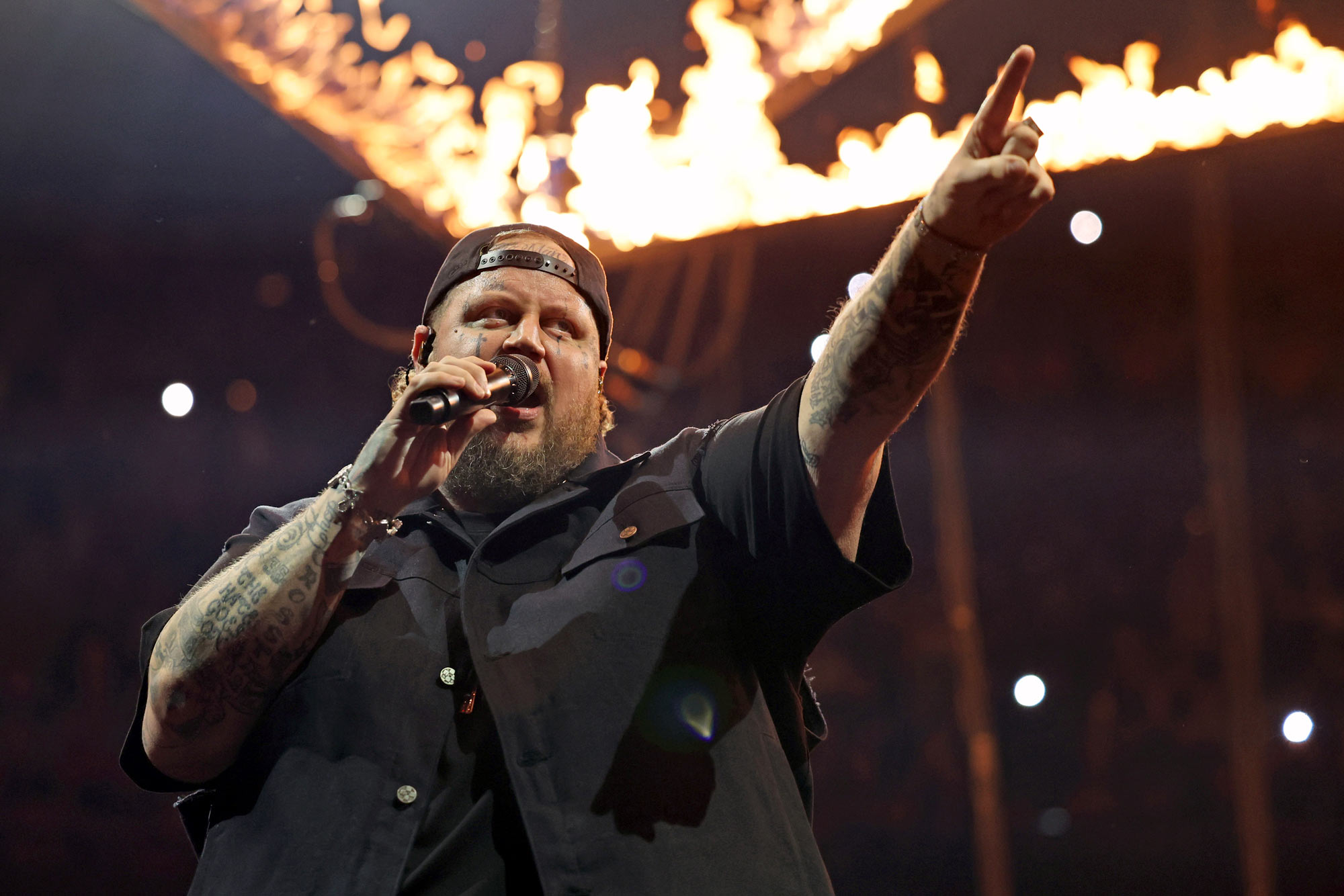 Close up with Jelly Roll singing with flames in the background