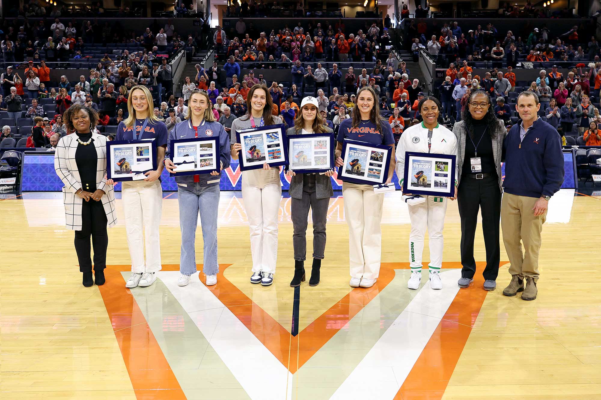 Chanel Craft Tanner, the director of the UVA Maxine Platzer Lynn Women’s Center, joins Olympians Emma Weber, Sky Dahl, Alex Walsh, Bridget Williams, Aimee Canny and Ashley Anumba, UVA Director of Athletics Carla Williams and UVA President Jim Ryan at center court at JPJ Arena.