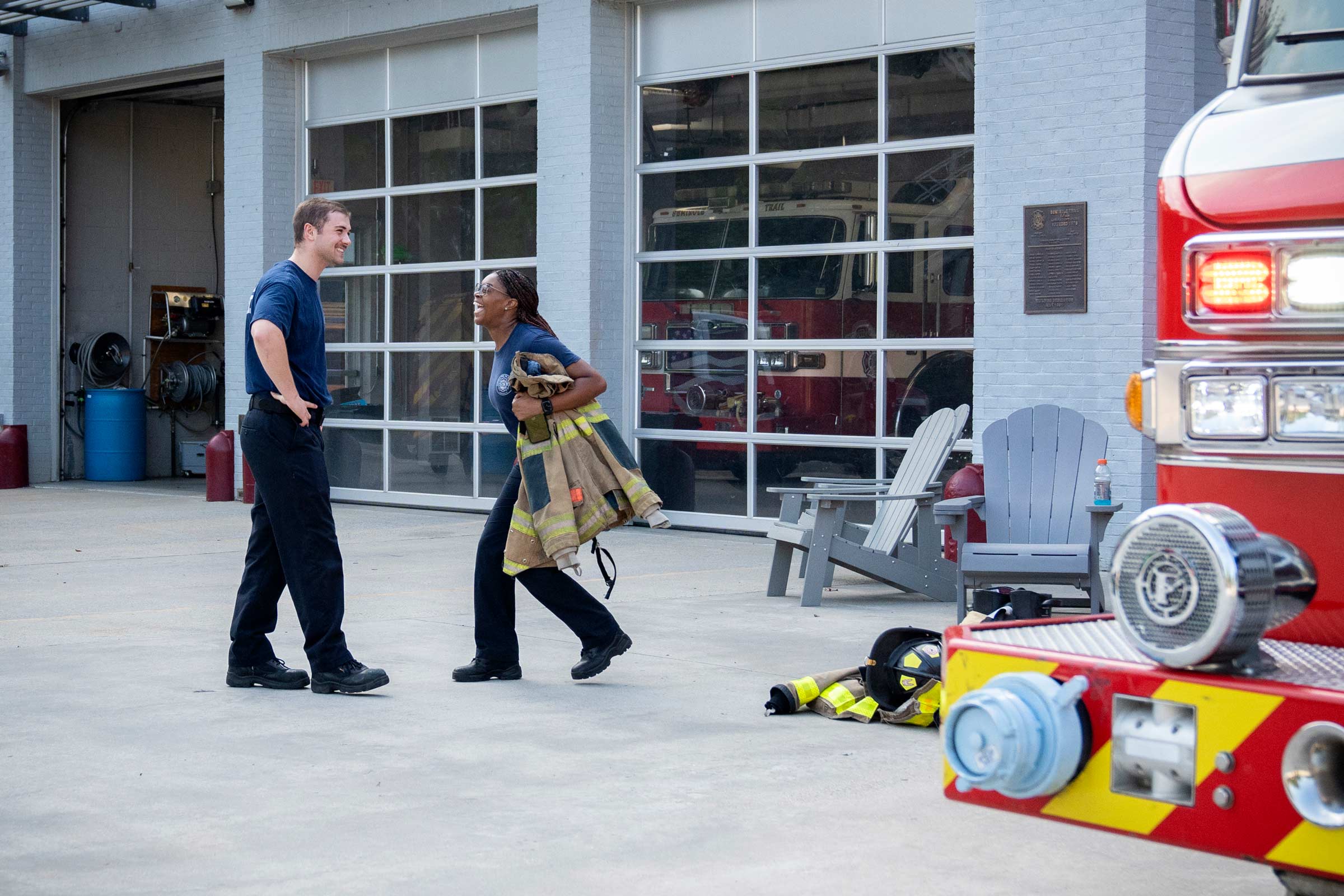 Two of the student firefighters laugh together in front of the firehouse