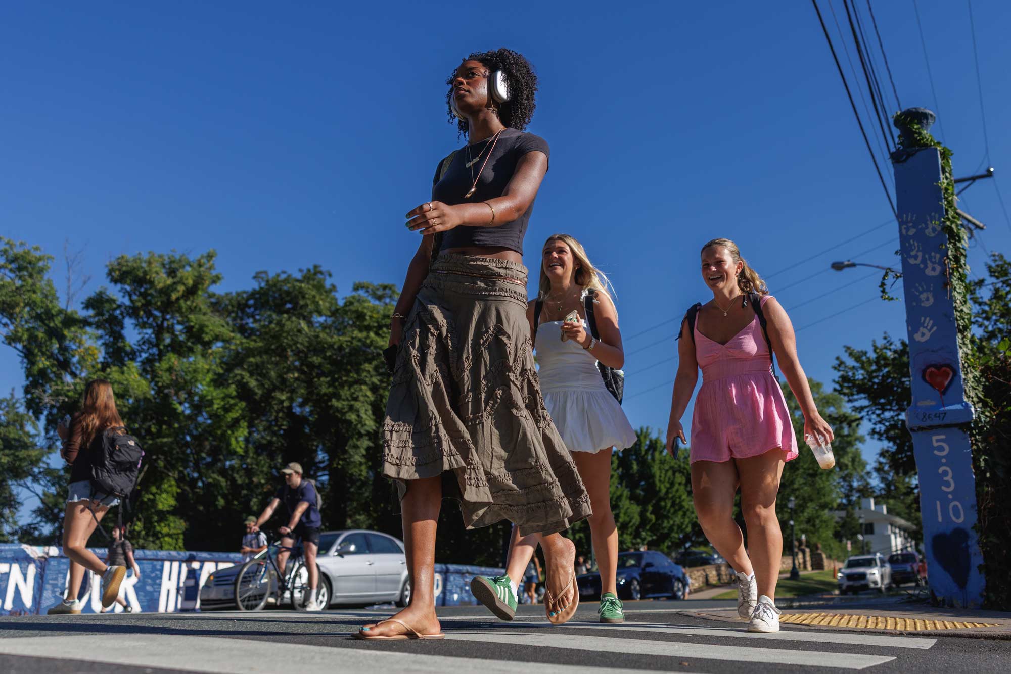 students in a crosswalk with a pillar painted with hand prints, hearts, and numbers that say "5•3•10