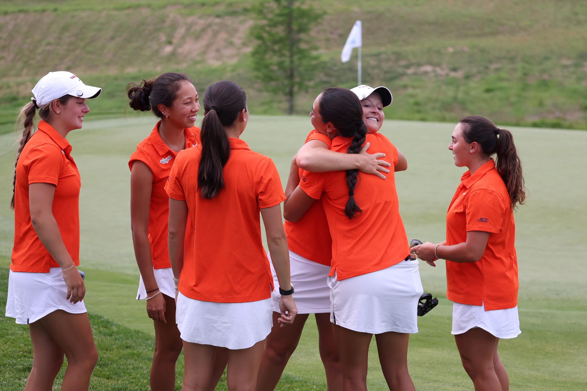 The UVA women’s golf team celebrating together on the green