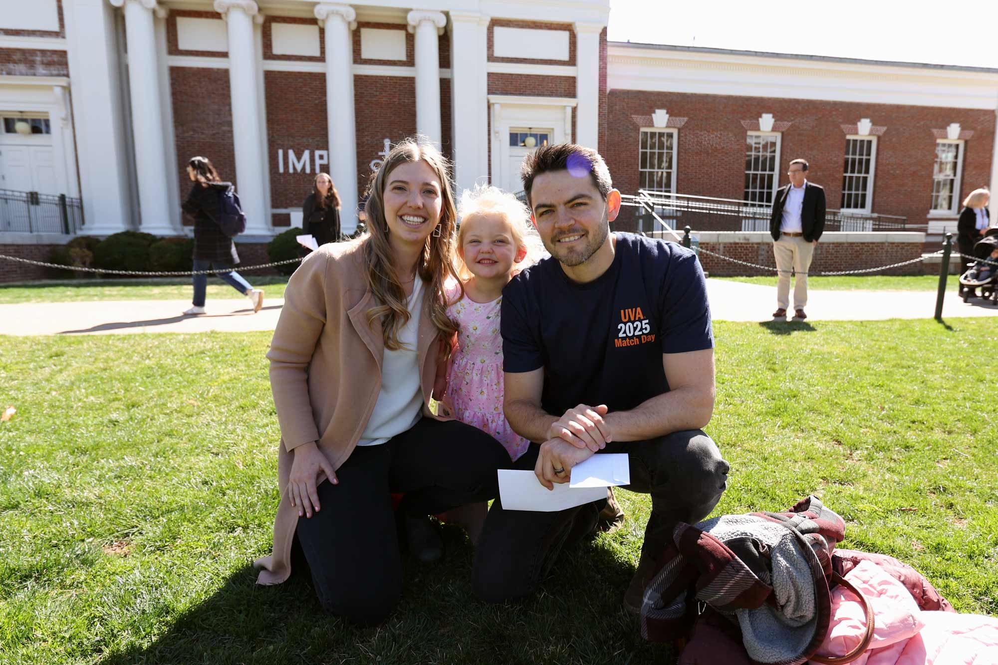 A student, his wife, and daughter smiling and looking at the camera