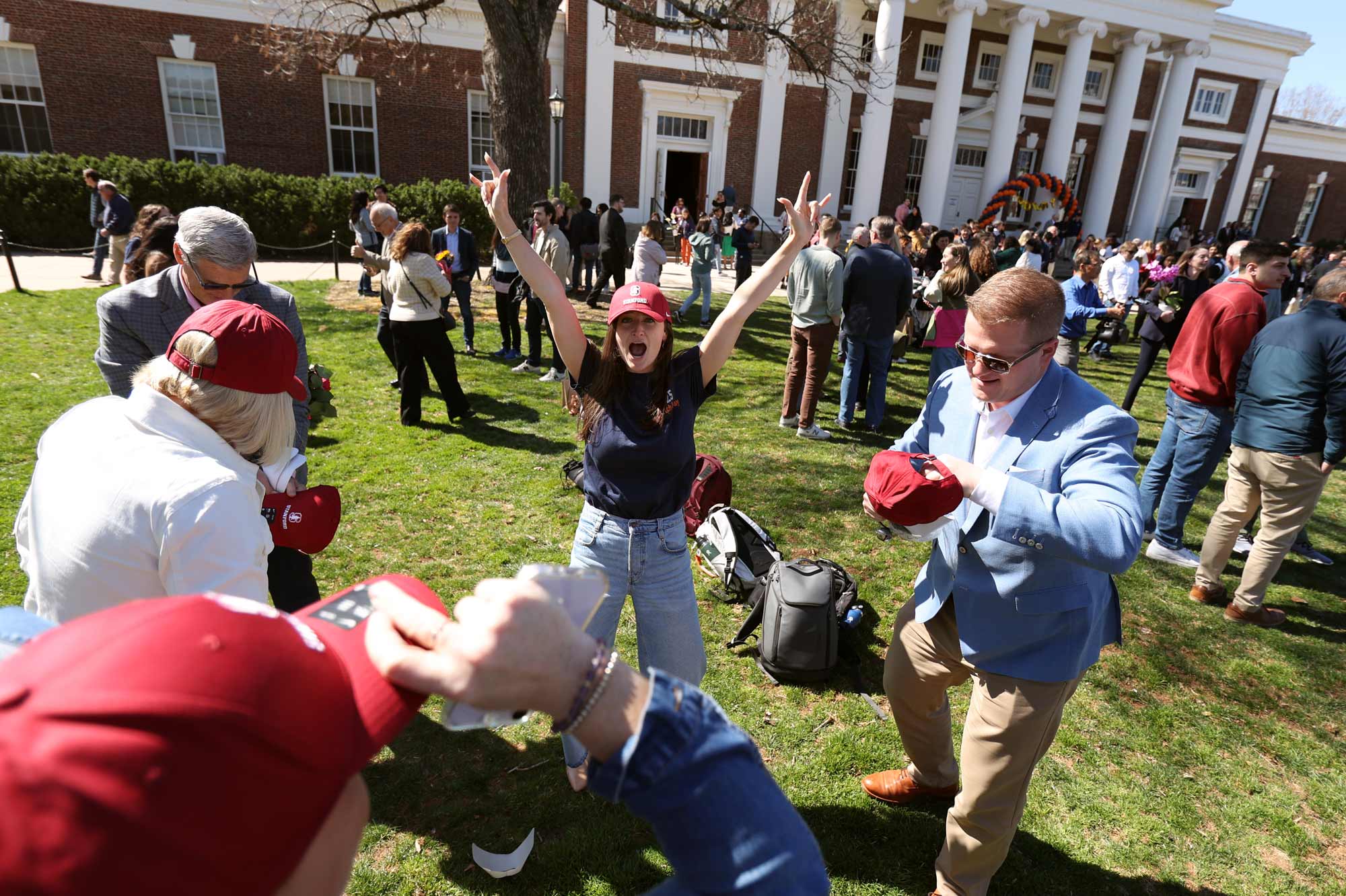 A joyful crowd at UVA's Match Day event, with students raising their hands in celebration as results are announced.