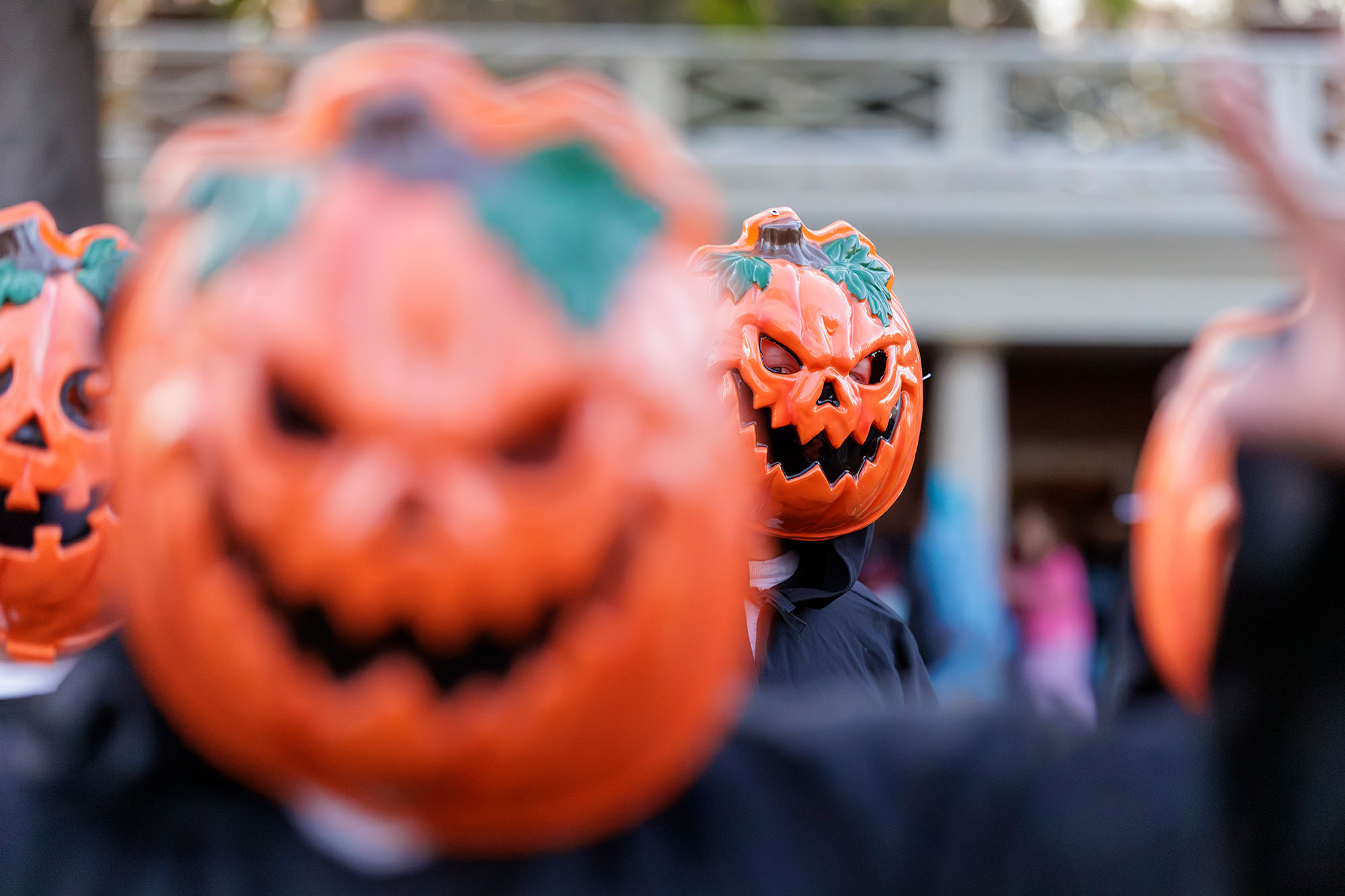 A group of students dressed in black capes and wearing plastic jack-o-lanterns on their heads participate in Trick-or-Treat on the Lawn.
