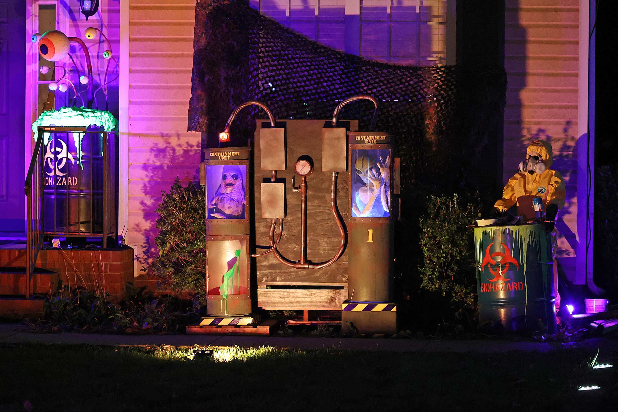 Two aliens being held in containment units, with glowing hazerdous materials nearby.