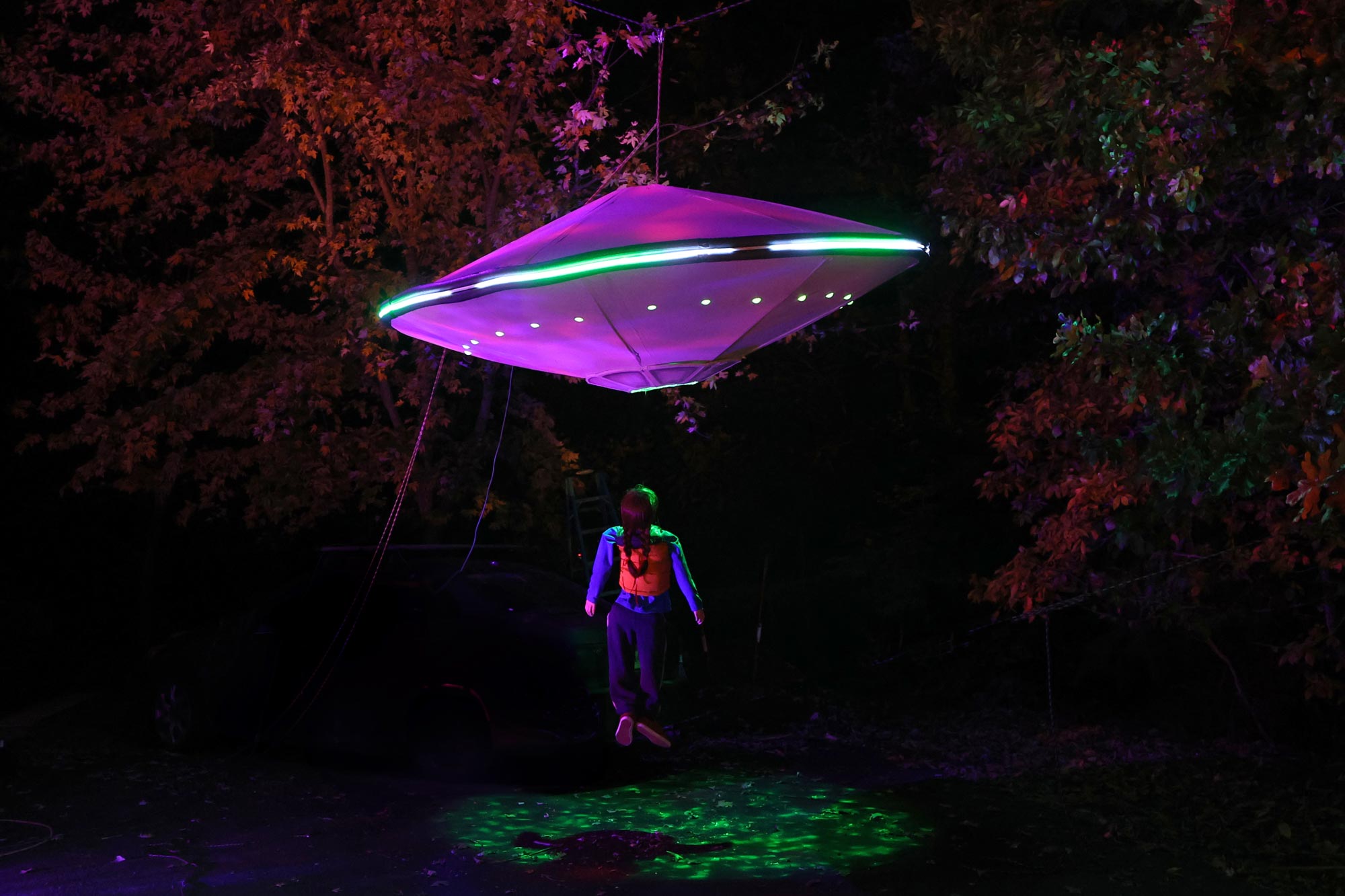 A UFO in mid-air pulling up a human.