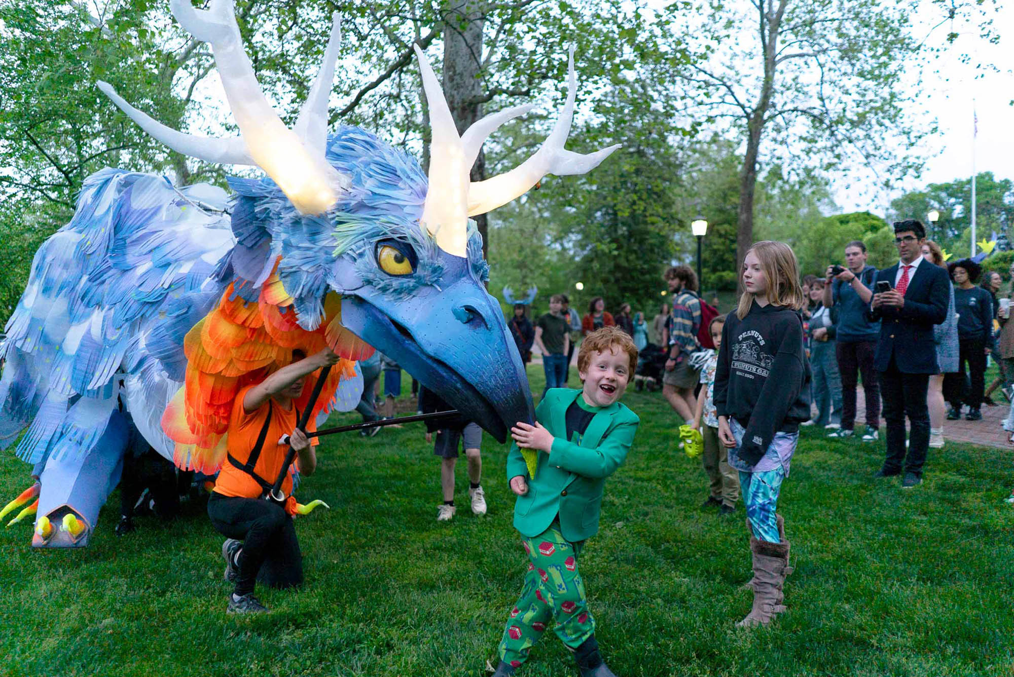 Celeste the moving creature puppet bends down to greet a kid before they run away with excitement