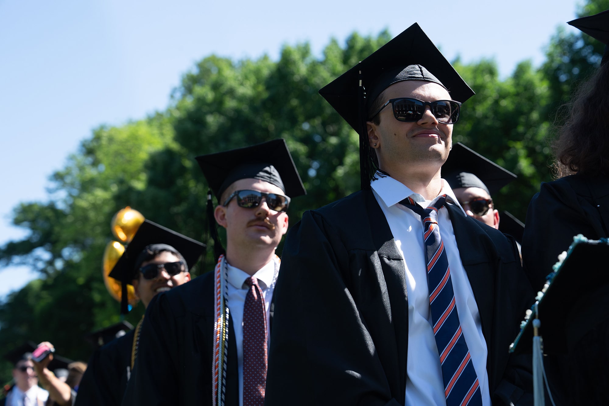 A row of 2025 graduates all in sunglasses during a beautiful and sunny ceremony