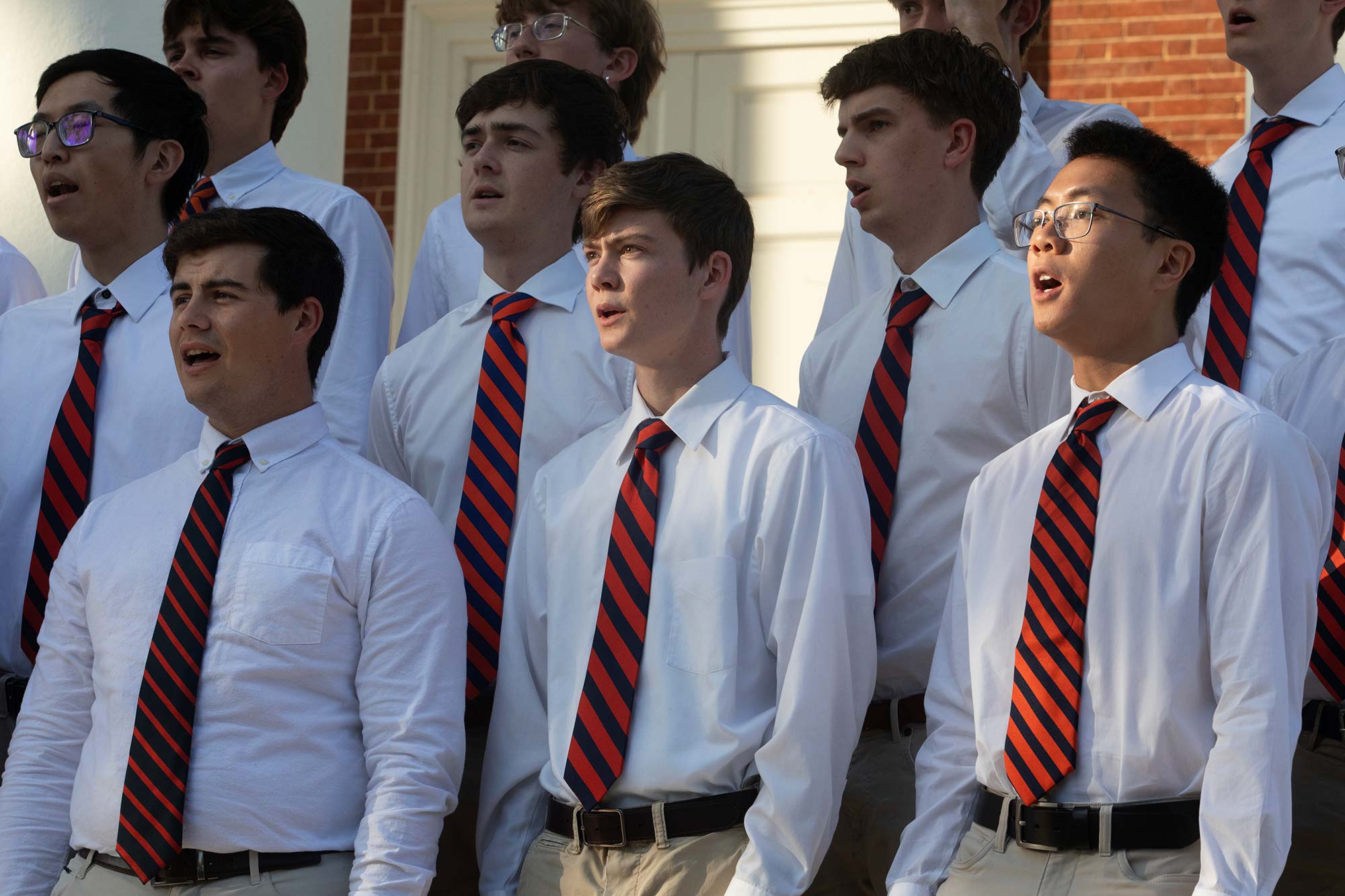University Students in white shirts and ties singing together.