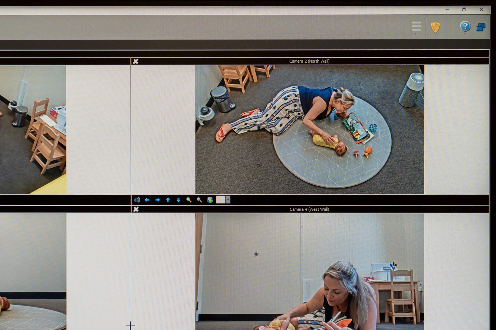 A computer interface showing different camera views of a mother playing with her baby on a floor mat