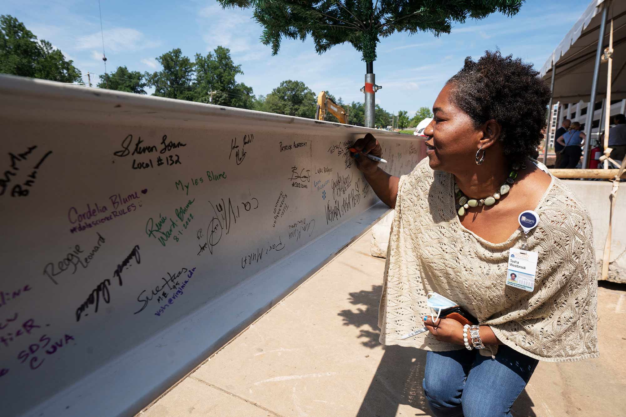 A woman signs her name onto a steel girder already covered in signatures
