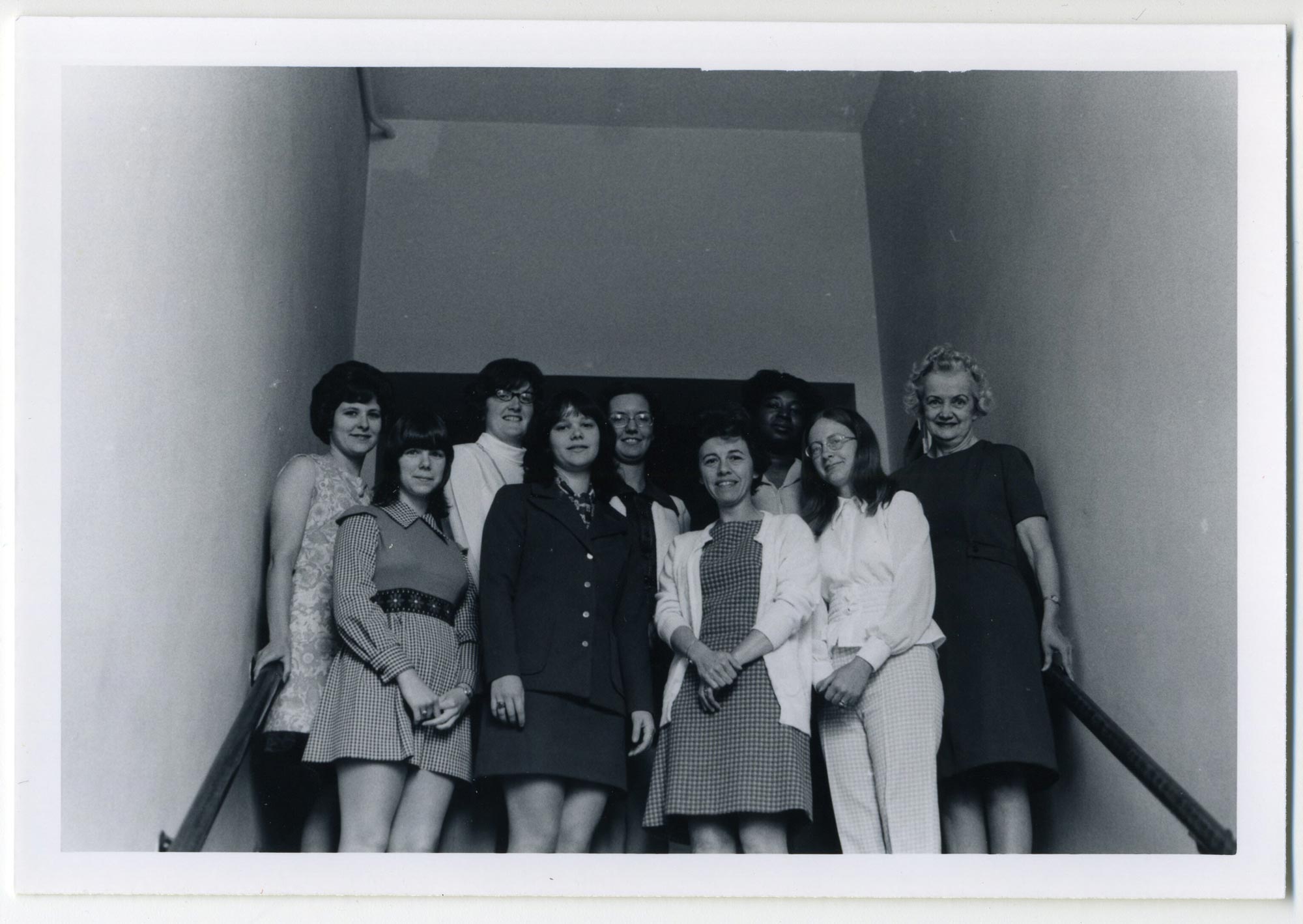 Nine women pose in a stairwell