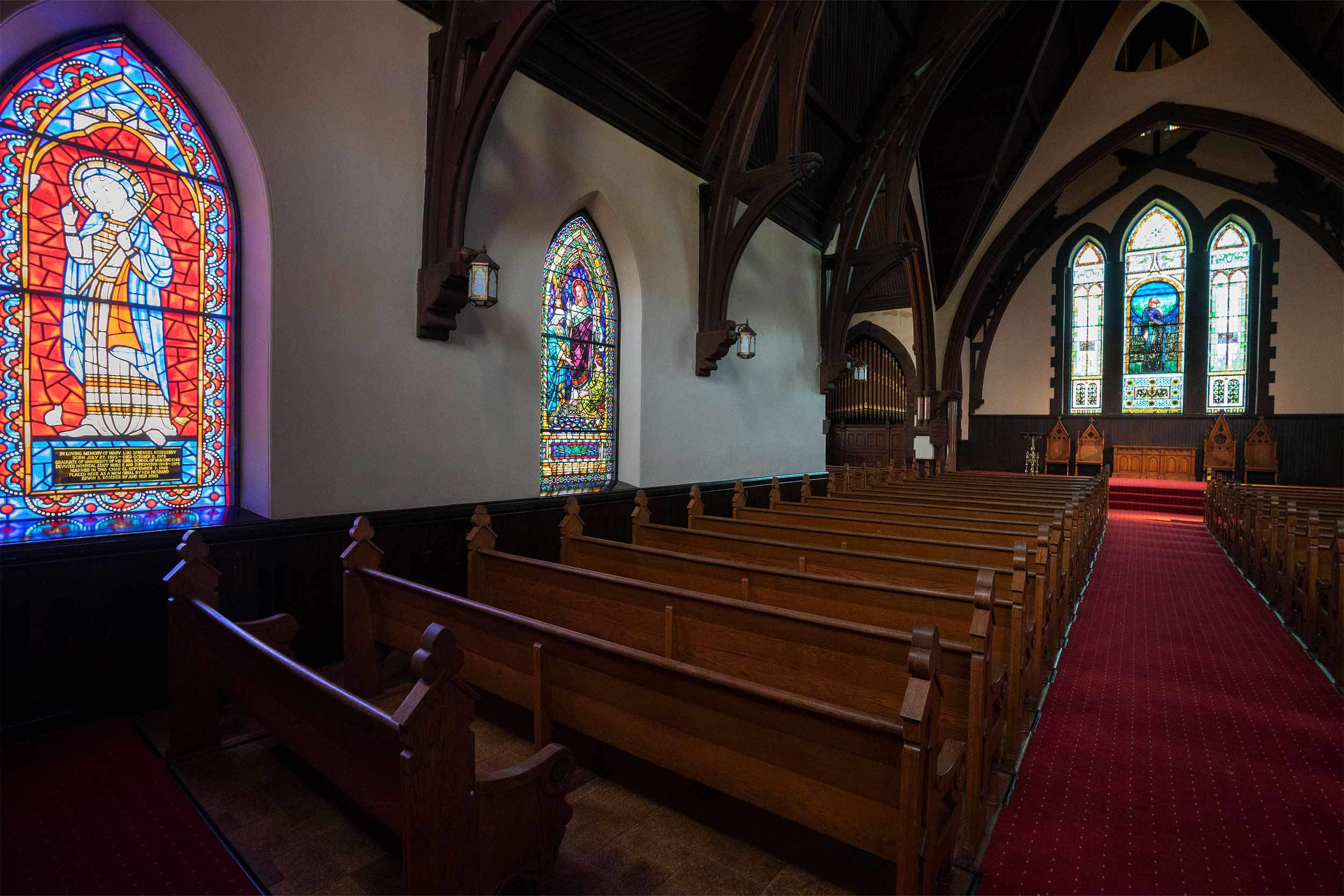 The interior of the chapel contains rows of oak pews, stained glass windows and a red carpeted aisle