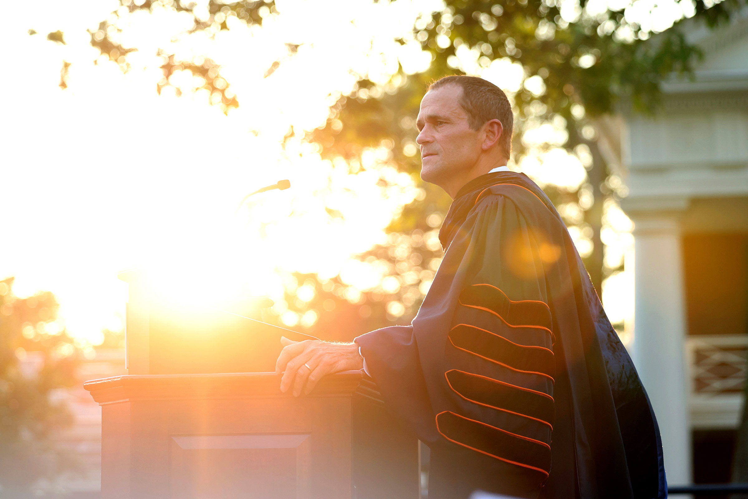 The sun glows behind UVA President Ryan as he speaks to the crowd gathered for convocation