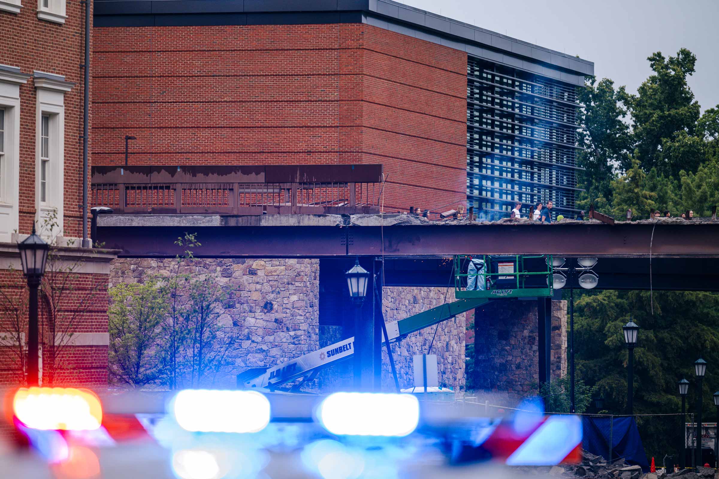 Flashing police lights are blocking the road due to bridge demolition.