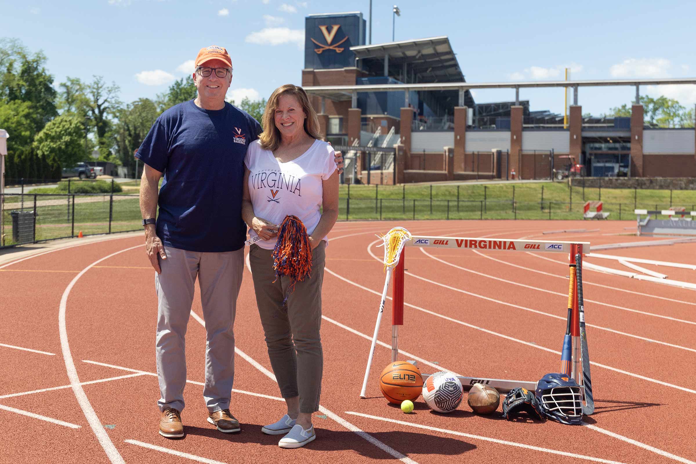 The Deckers stand on a UVA track with various sports equioment