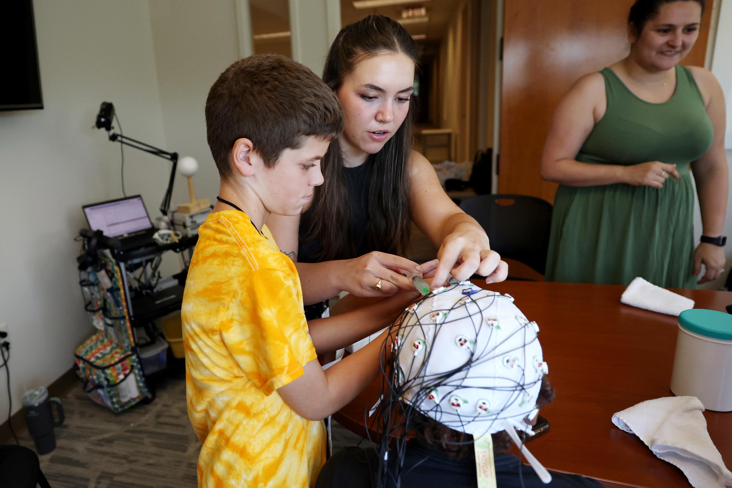 An EEG cap is demonstrated to a kid by a UVA student 