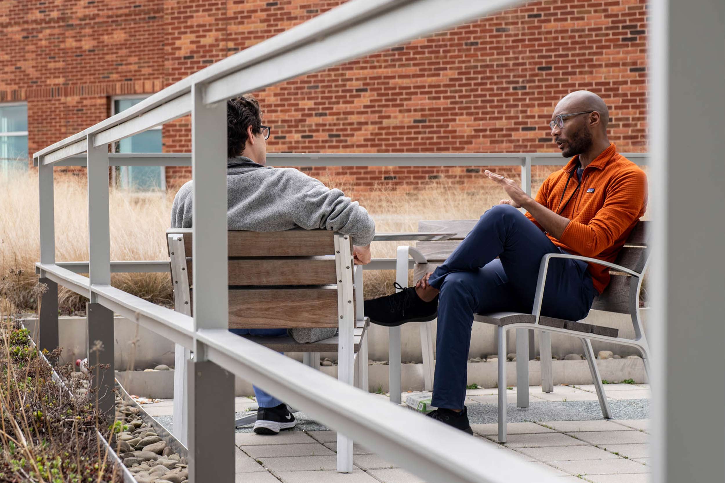 Dr. Taison Bell sitting on a patio outside talking with a student