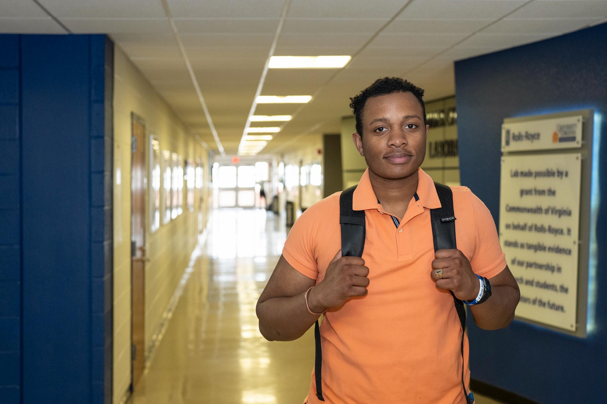 Joshua Franklin, wearing a backpack, poses for a portrait in a hallway.