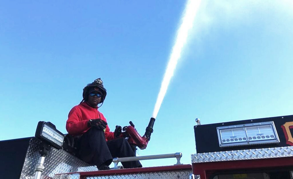 Dorsey holds a firehose as it sprays water