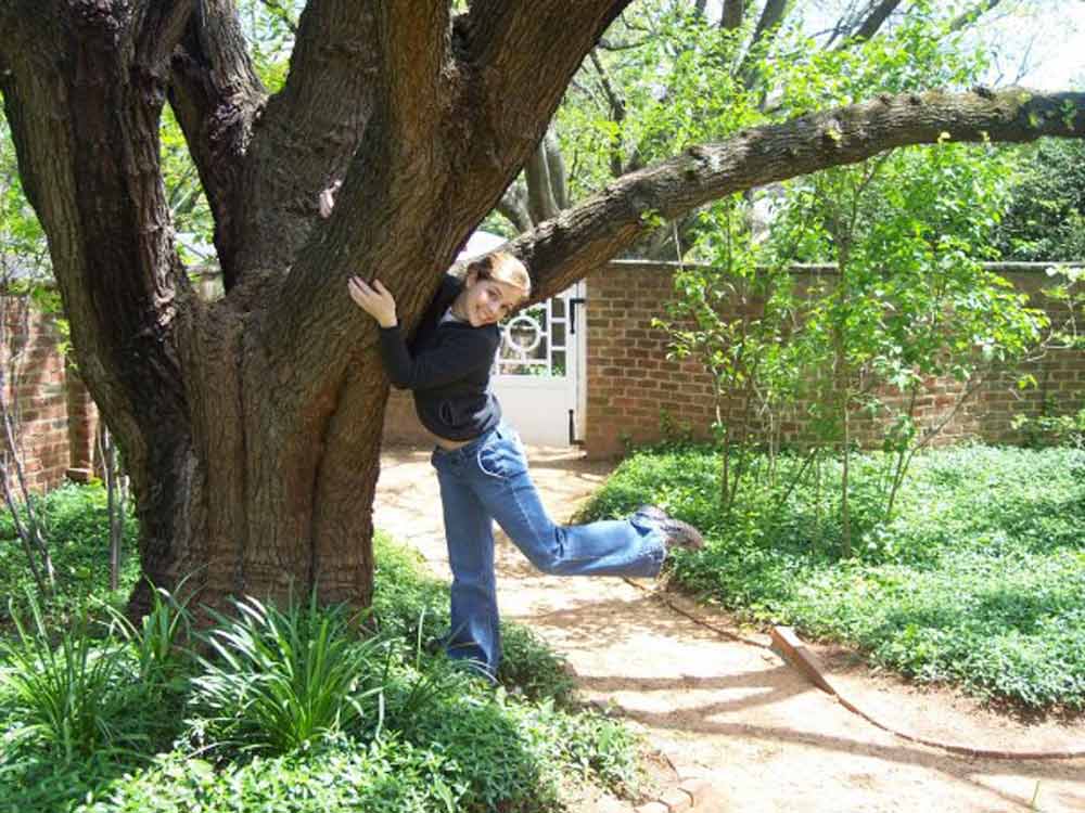 Jen Lilley as a student at UVA posing by a tree in the University gardens