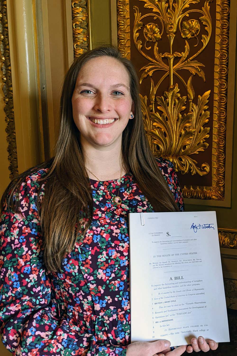 Victoria Long Rubin, smiling, holds a document.