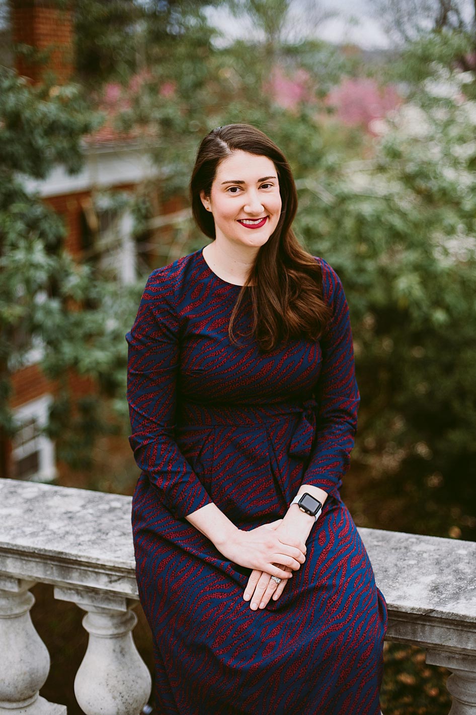 Lauren Miller Simkins sits on a marble bench and smiles at the camera