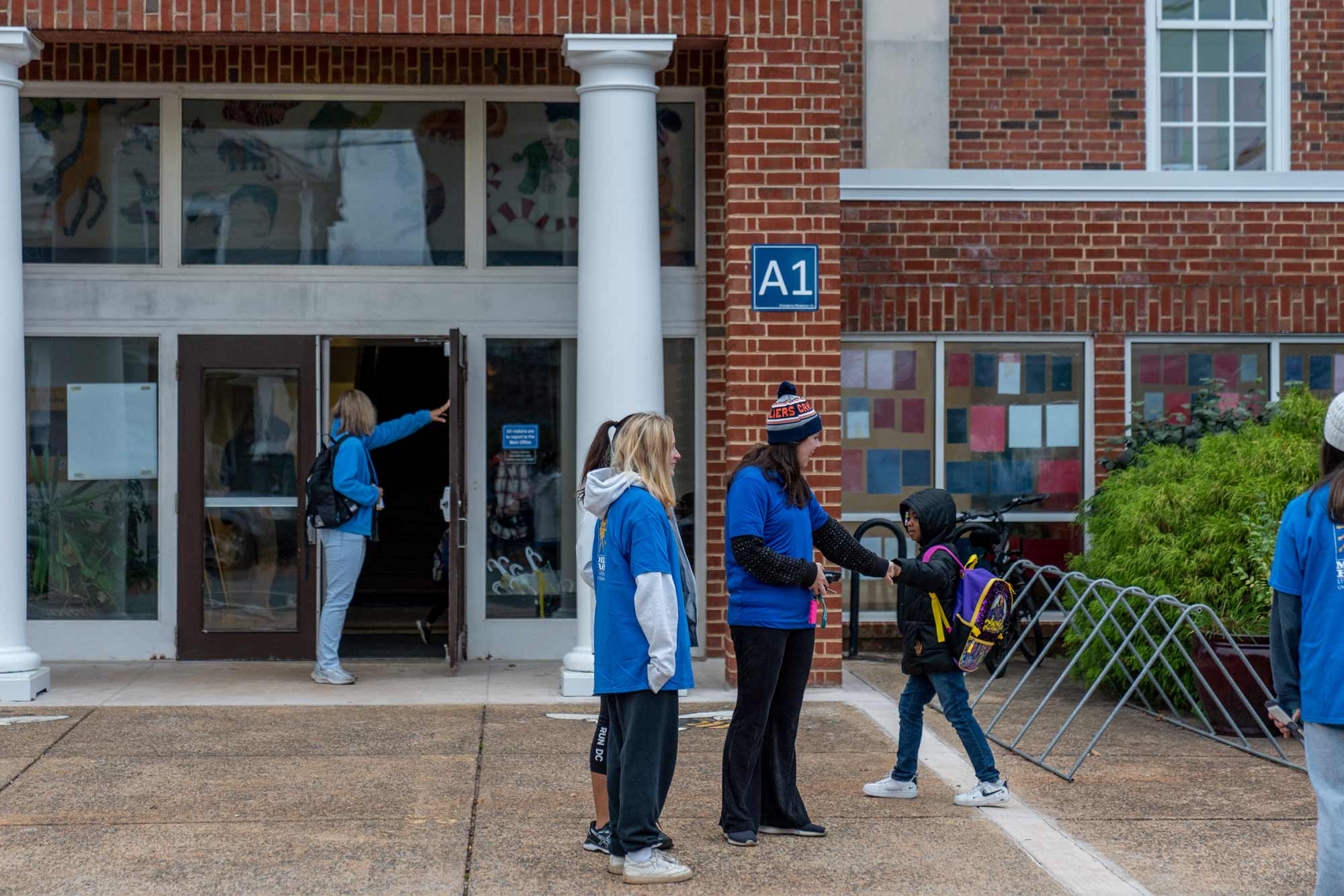 UVA students greeting elementary students outside of a building