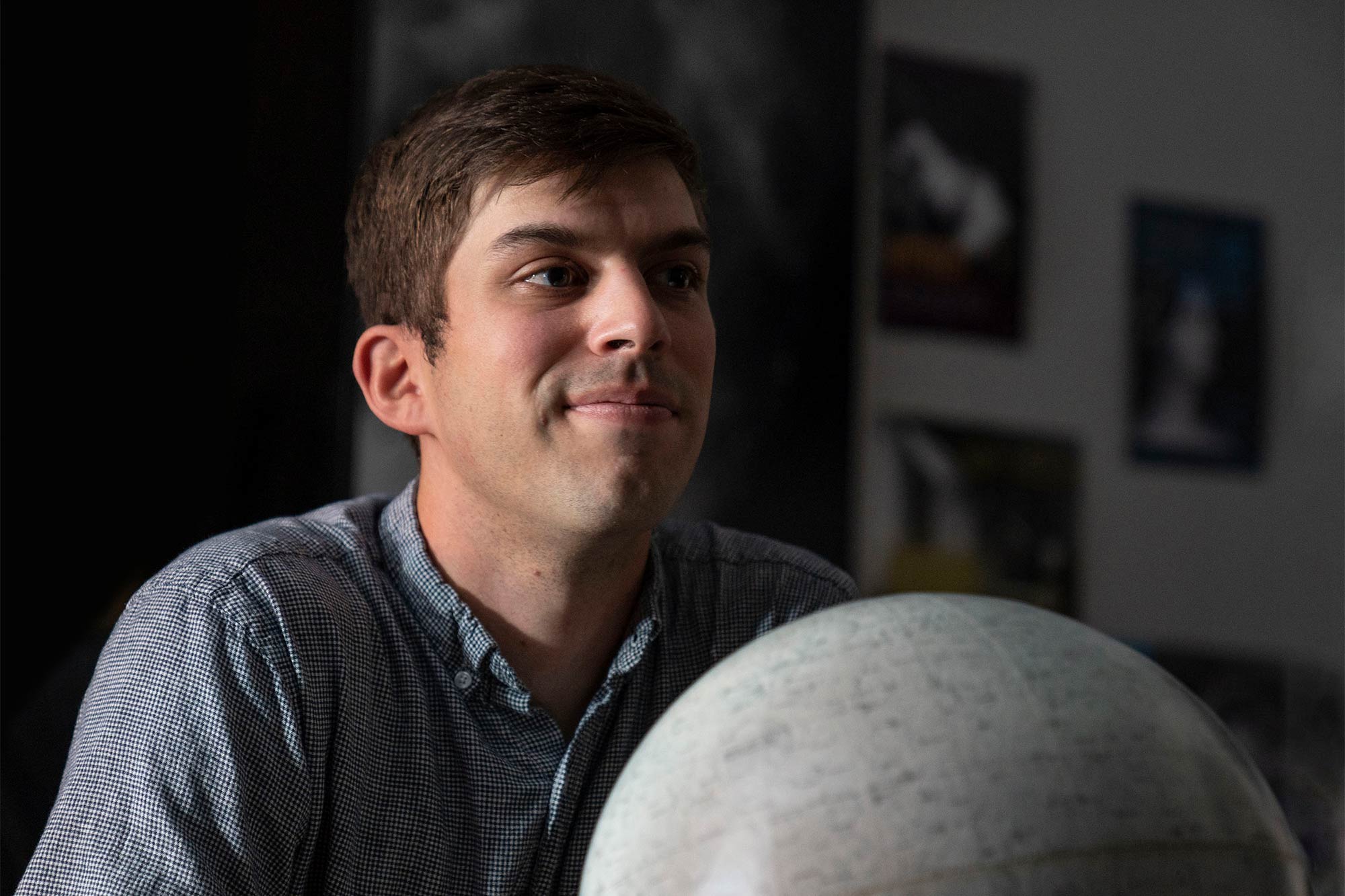 Matt Pryal, behind a lunar globe, looks off camera and smiles