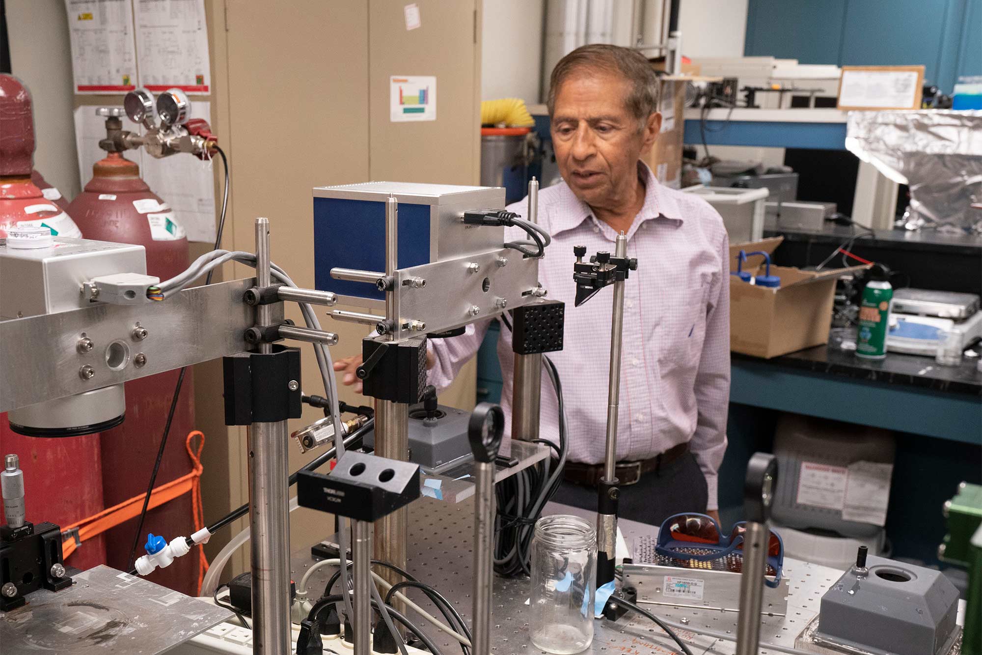 In an engineering lab, Gupta examines a stainless steel machine on a workbench