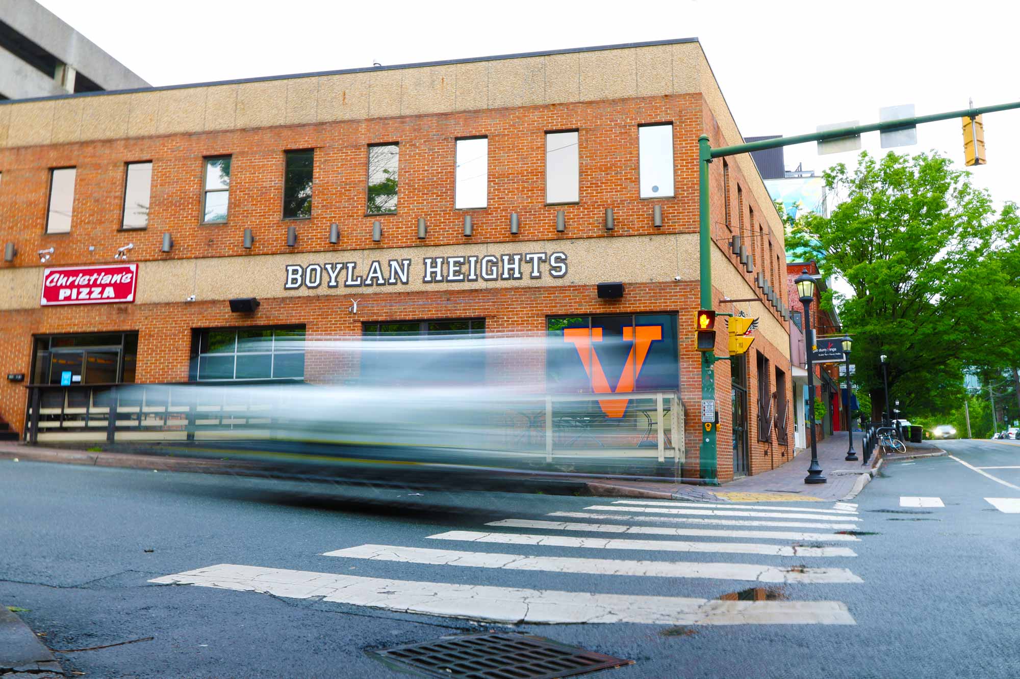 A blurred car moves by the big V logo in front of the Boylan Heights building