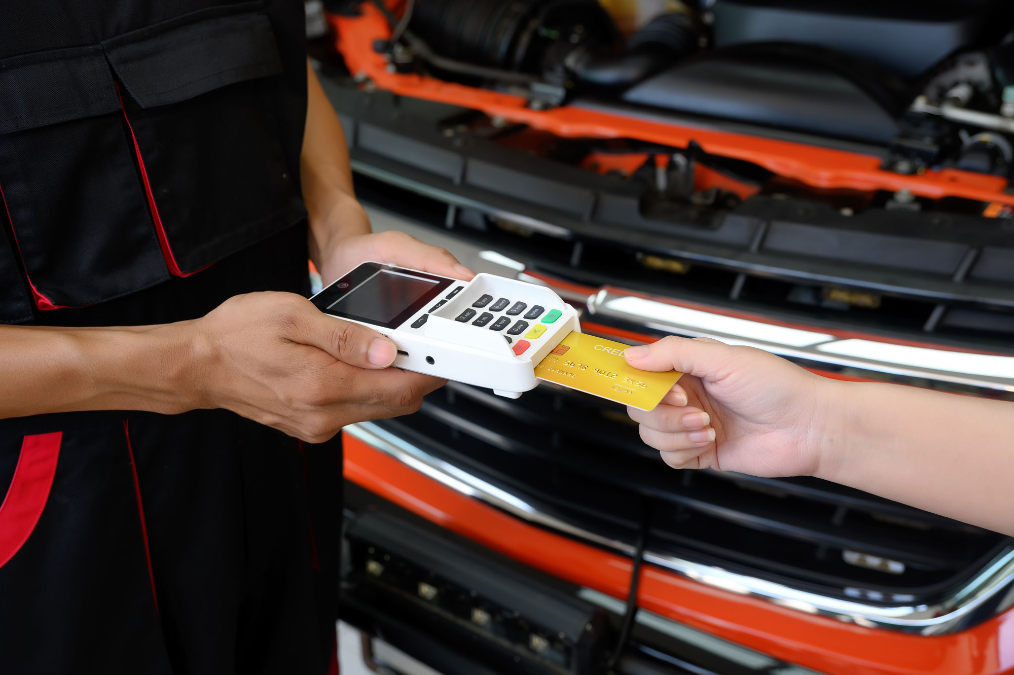 Someone inserting their card into a reader to pay for an auto repair