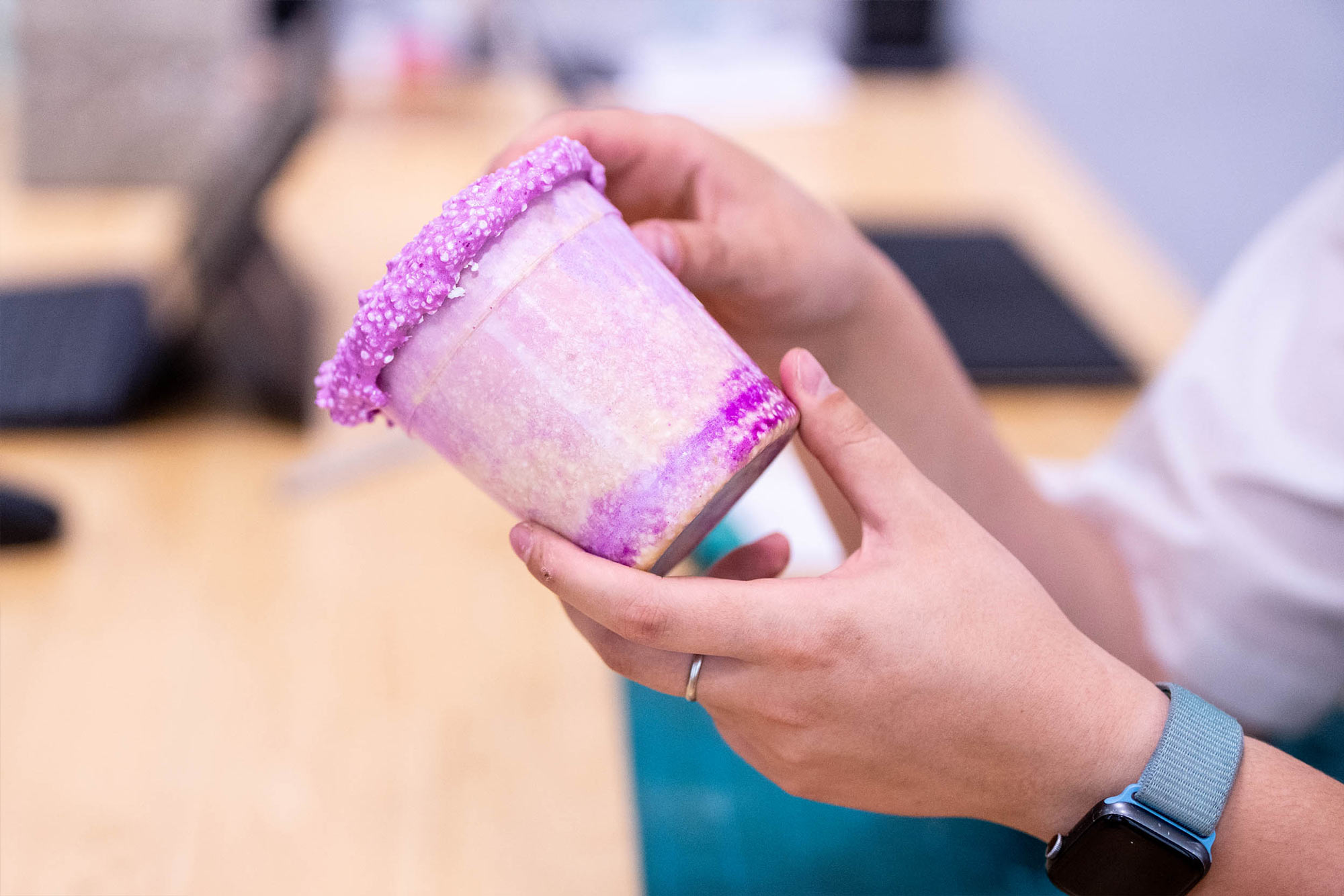 A close up of research assistant holding out a pink foam cup