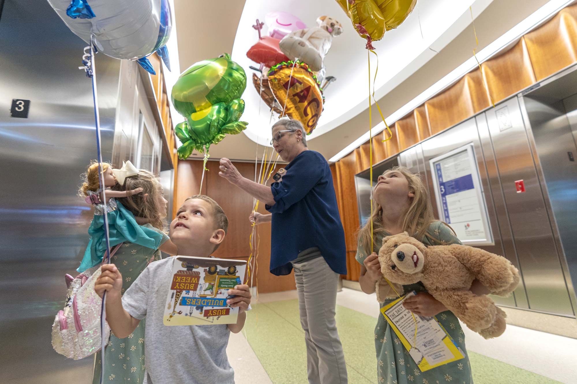 Joshua Leslie, foreground, admires his shark balloon with two friends who also hold balloons