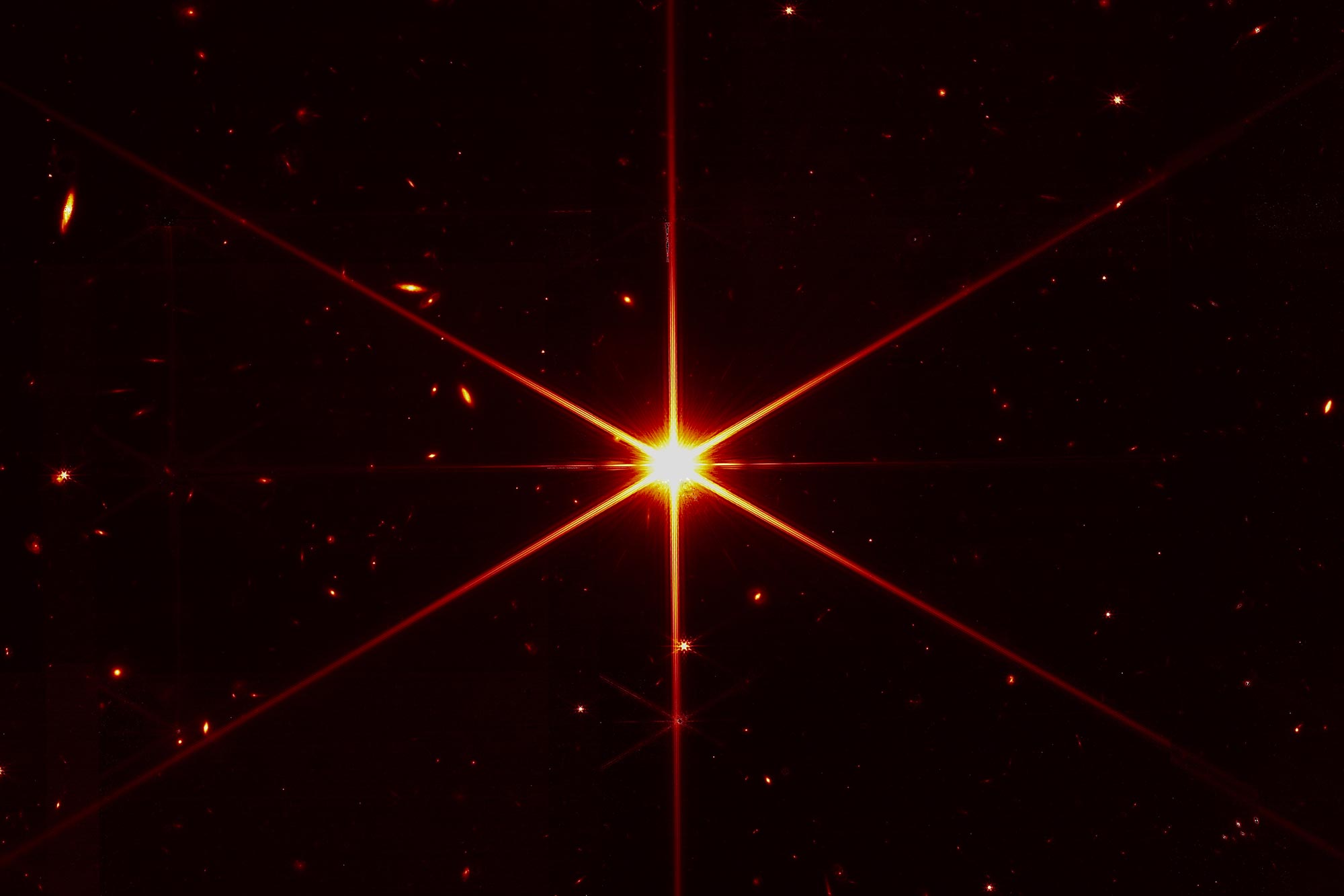 A bright star surrounded by faint images of other stars and distant galaxies