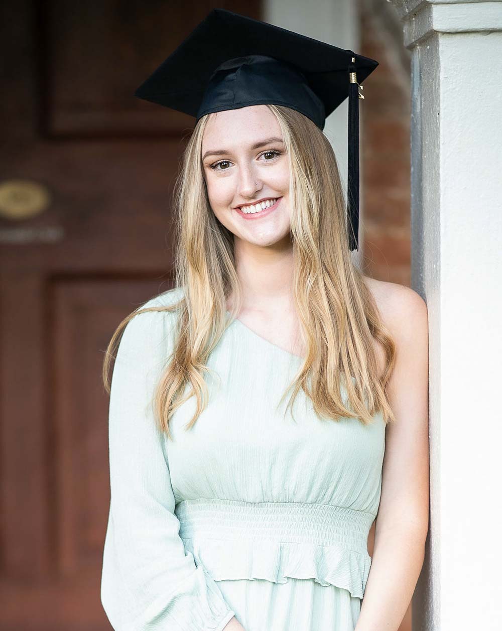 Olivia Hazelwood wears a graduation cap and smiles at the camera