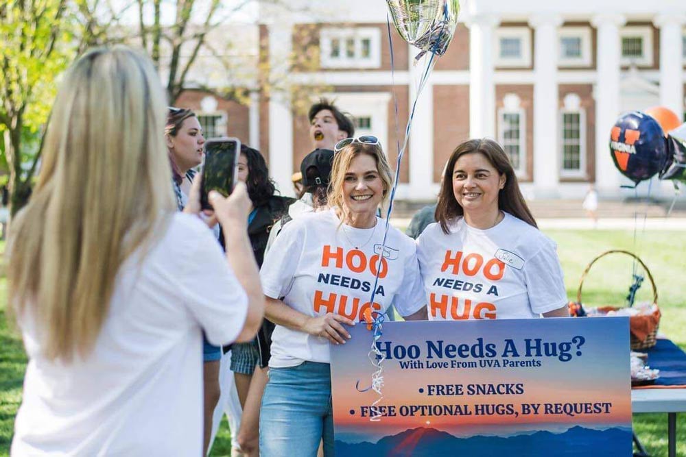 UVA moms Mellony Spake Harris and Julie Ramirez Hawkins holding up a sign thay says Hoo needs a hug?