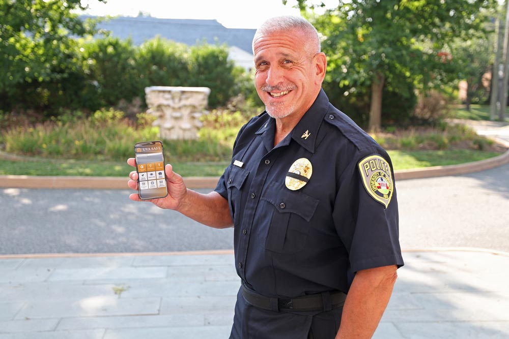 A portrait of Tim Longo holding up a smartphone with the safety app displayed on it