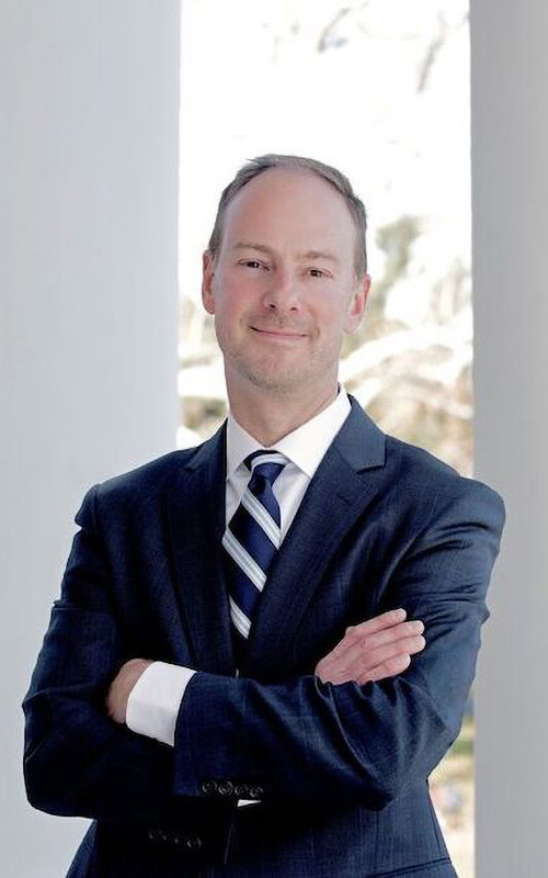 Todd Sechser stands with his arms crossed and smiles at the camera